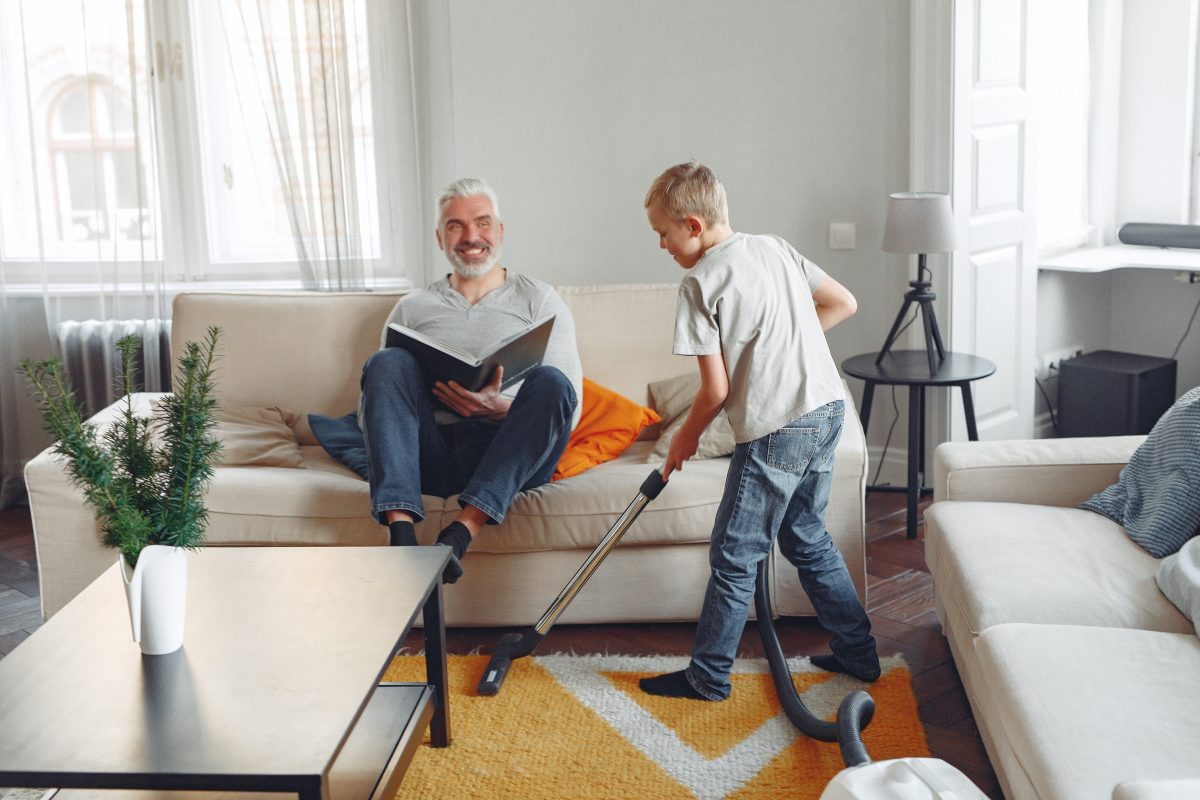 Photo by Gustavo Fring with a young boy cleaning the carpet in the living room with his dad.