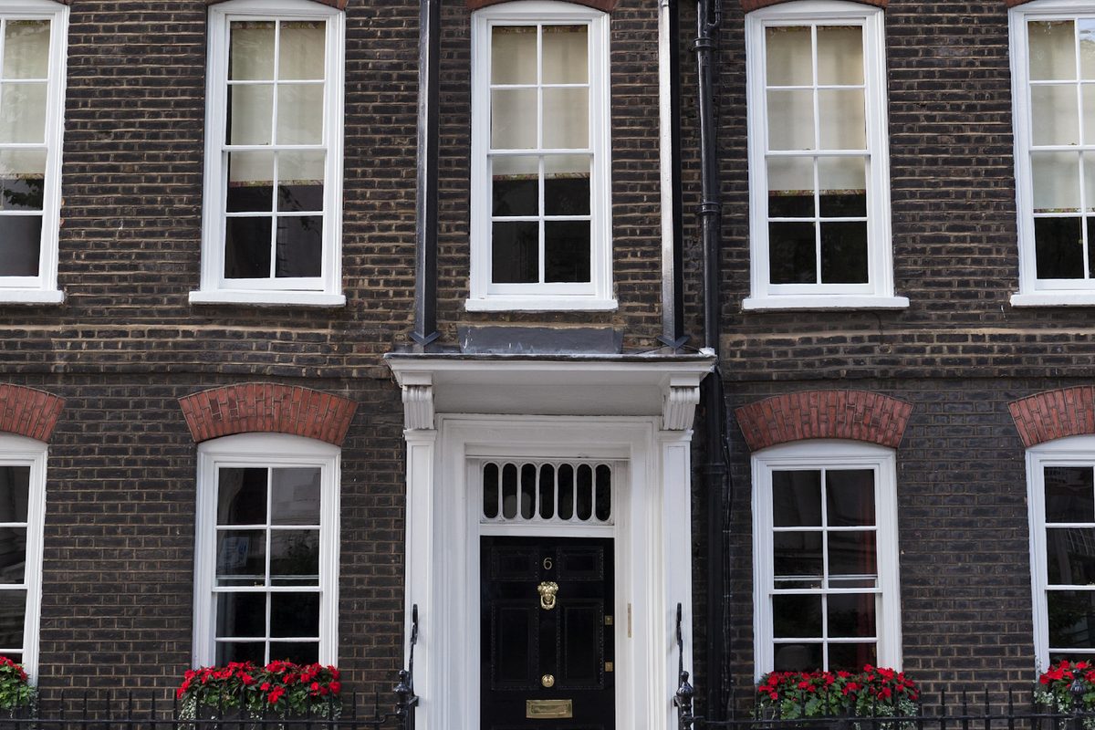 Georgian brick townhouse with black front door and railings in Central London