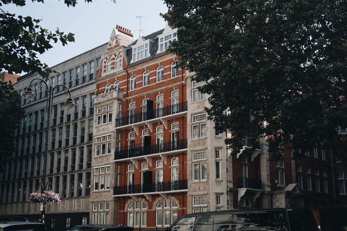 Period red-brick and stone buildings on a tree-lined London street